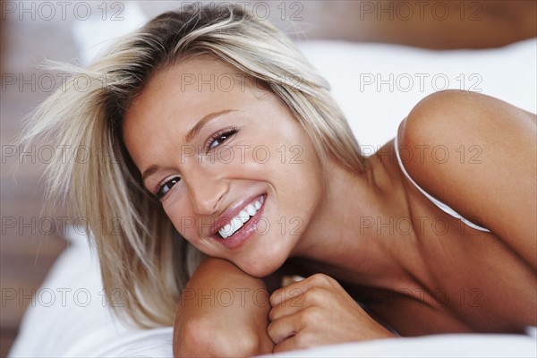 Blonde woman lying on bed. Photographe : momentimages