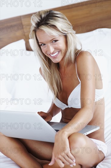 Woman wearing lingerie and typing on laptop. Photographe : momentimages