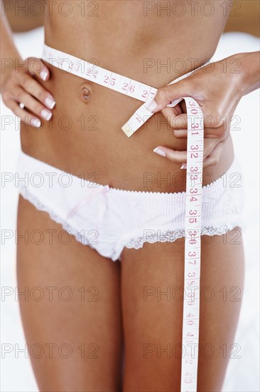 Woman measuring her waist. Photographe : momentimages