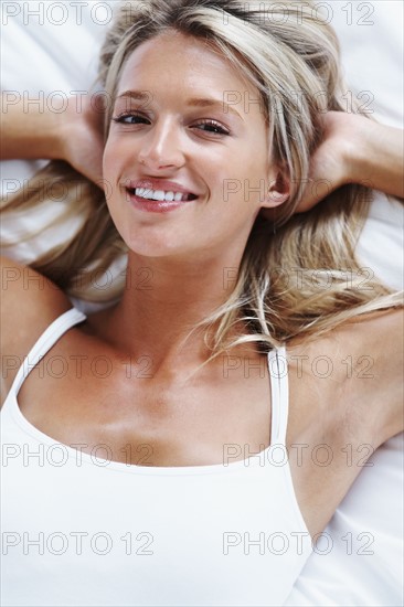 Blonde woman lying on bed. Photographe : momentimages