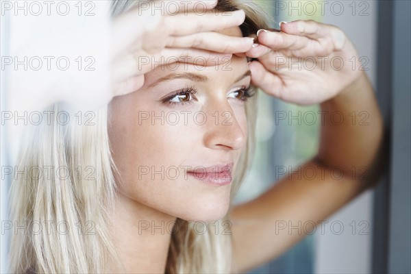 Blonde woman looking out window. Photographe : momentimages