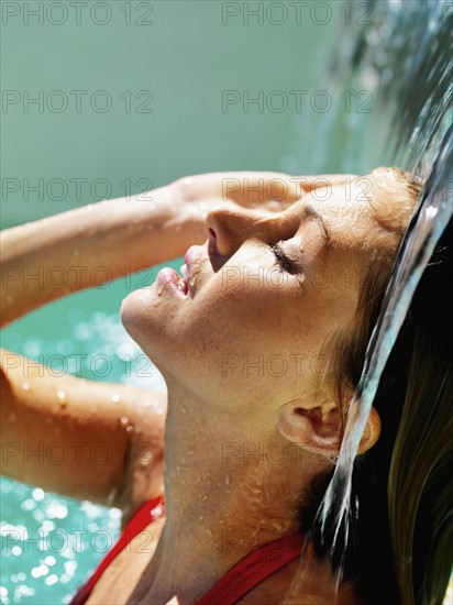 Woman under waterfall in pool. Photographe : momentimages