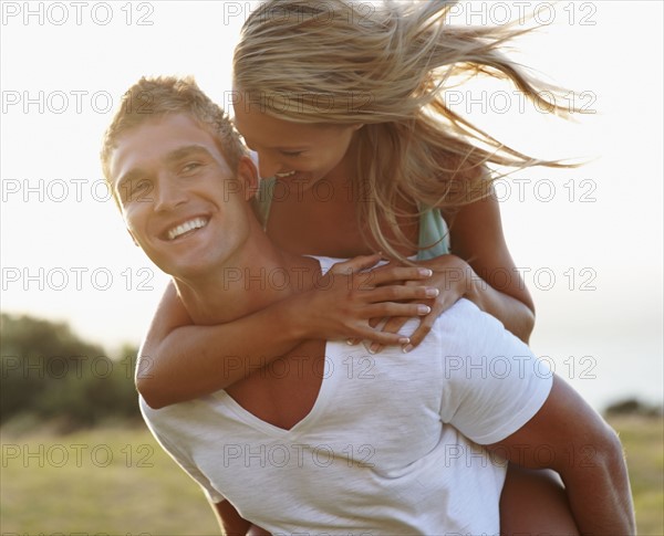 Man giving girlfriend a piggy back ride. Photographe : momentimages