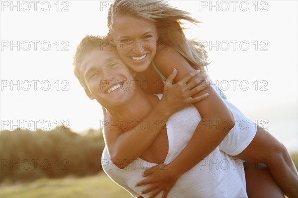 Man giving girlfriend a piggy back ride. Photographe : momentimages