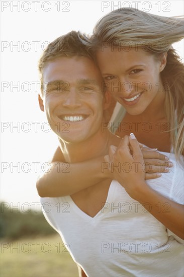 Man giving girlfriend a piggy back ride. Photographe : momentimages