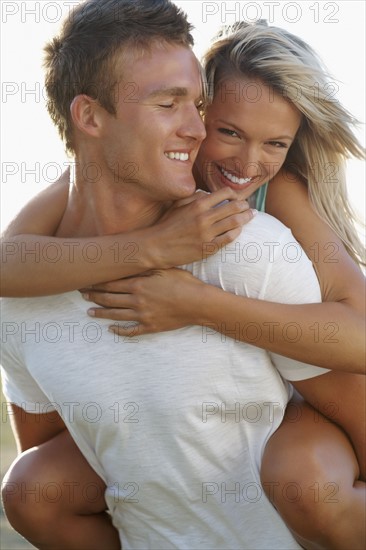 Man giving girlfriend a piggy back ride. Photographe : momentimages