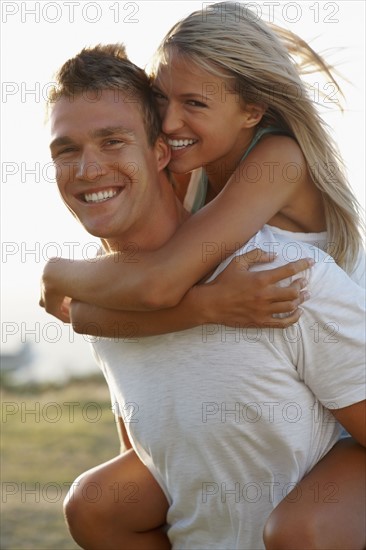 Man giving girlfriend a piggy back ride. Photographe : momentimages