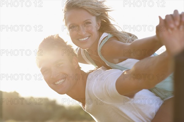 Man giving girlfriend a piggy back ride. Photographe : momentimages