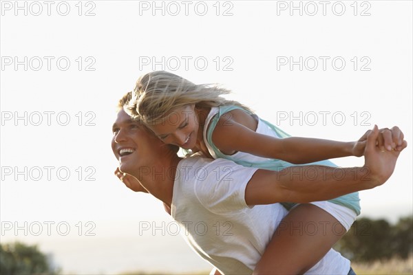 Man giving girlfriend a piggy back ride. Photographe : momentimages