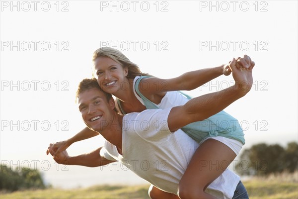 Man giving girlfriend a piggy back ride. Photographe : momentimages