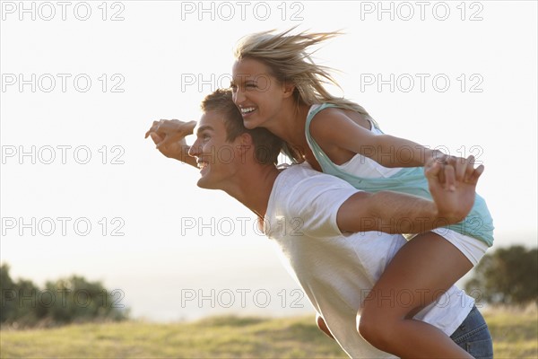 Man giving girlfriend a piggy back ride. Photographe : momentimages