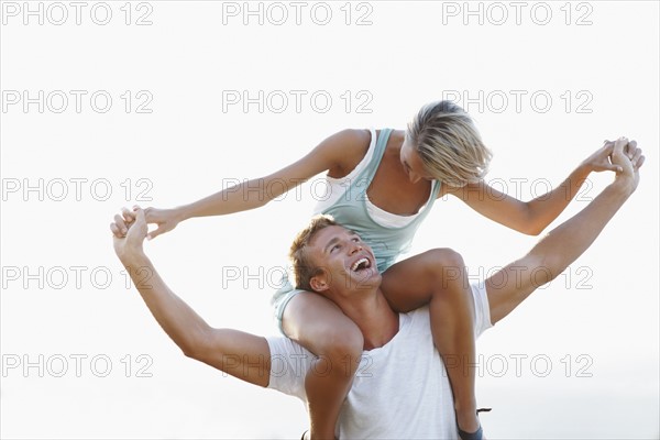 Man giving girlfriend a shoulder ride. Photographe : momentimages