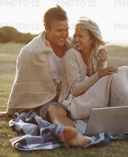 Couple looking at laptop outdoors. Photographe : momentimages