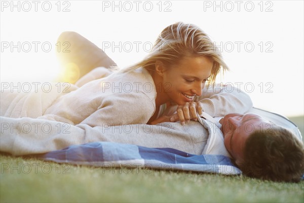 Couple lying down on picnic blanket. Photographe : momentimages