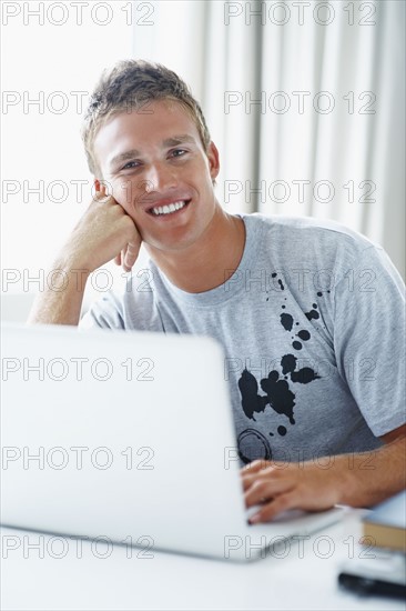 Young man working on laptop. Photographe : momentimages