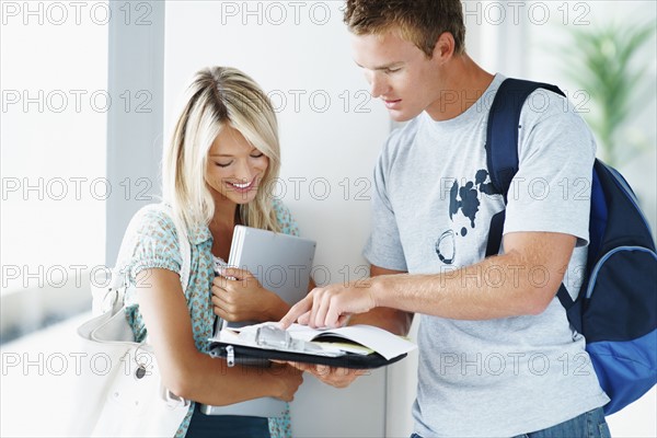 Students looking at book together. Photographe : momentimages