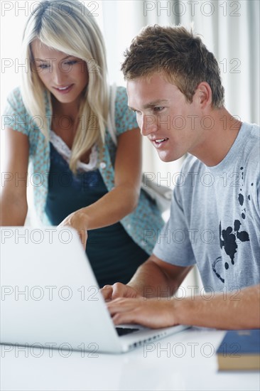 College students looking at laptop. Photographe : momentimages