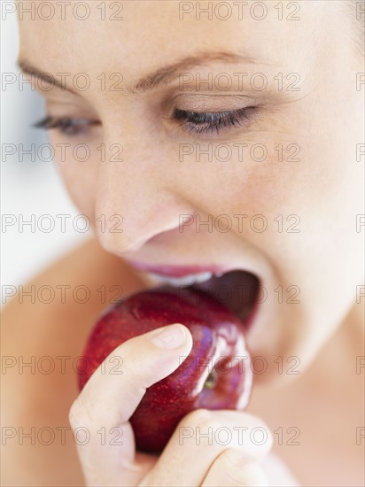 Woman eating an apple. Photographe : momentimages