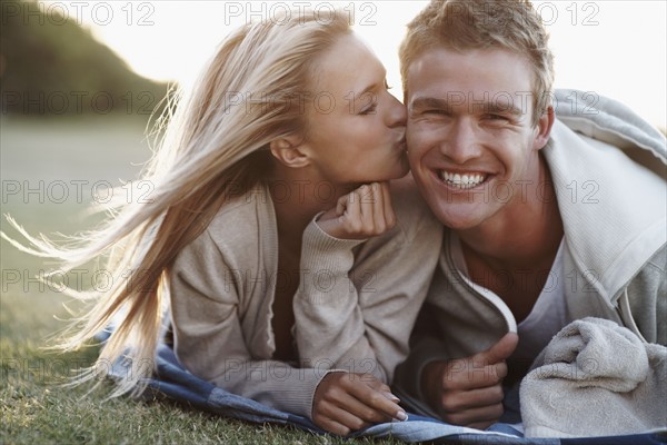 Woman kissing boyfriend. Photographe : momentimages