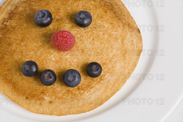 Pancake with smiley face made from blueberries and raspberry. Photographe : Kristin Lee