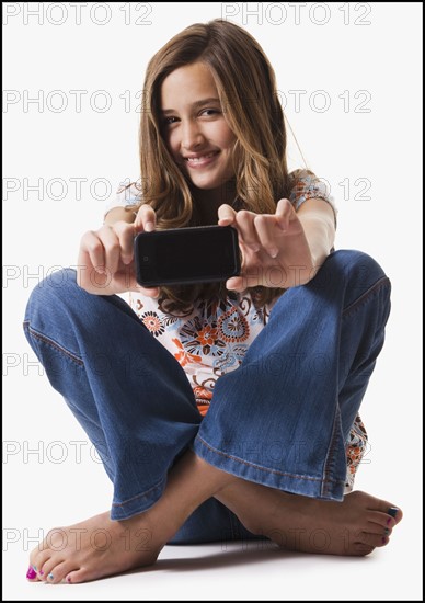 Young girl holding cellular phone. Photographe : Mike Kemp