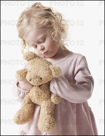 Tired young girl holding teddy bear. Photographe : Mike Kemp