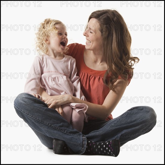 Mother holding daughter in her lap. Photographe : Mike Kemp