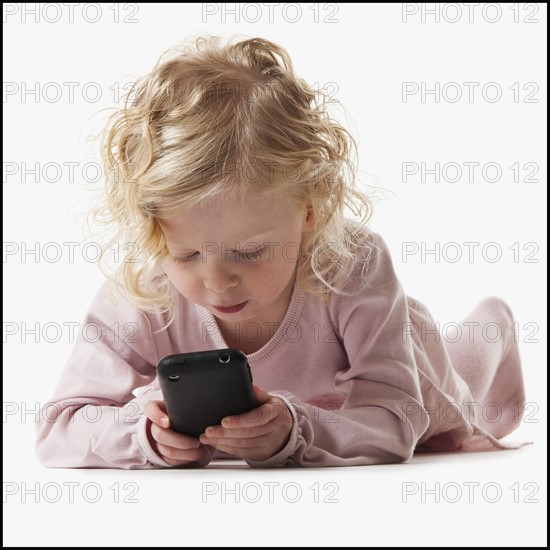 Young girl playing with a cellular phone. Photographe : Mike Kemp