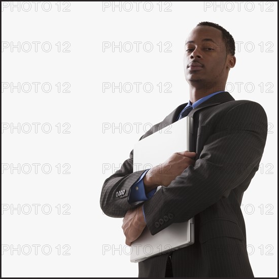 Serious businessman holding a laptop computer. Photographe : Mike Kemp
