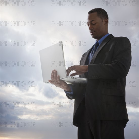 Businessman typing on a laptop computer. Photographe : Mike Kemp