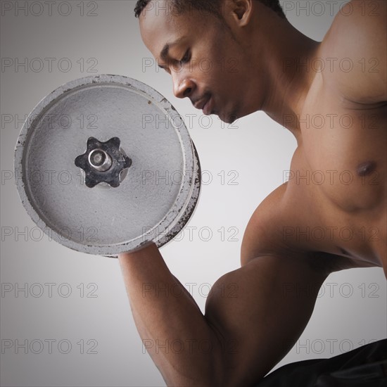 Muscular man lifting a dumbbell. Photographe : Mike Kemp