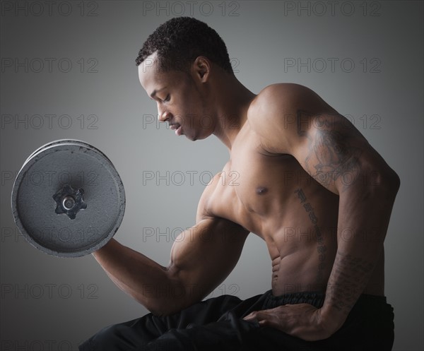 Muscular man lifting a dumbbell. Photographe : Mike Kemp