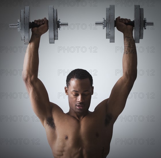 Muscular man lifting dumbbells. Photographe : Mike Kemp