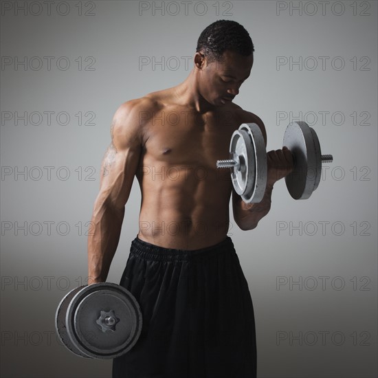 Muscular man lifting dumbbells. Photographe : Mike Kemp