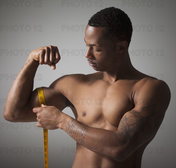 Man measuring his triceps. Photographe : Mike Kemp