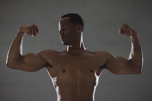 Physically fit man flexing his triceps. Photographe : Mike Kemp