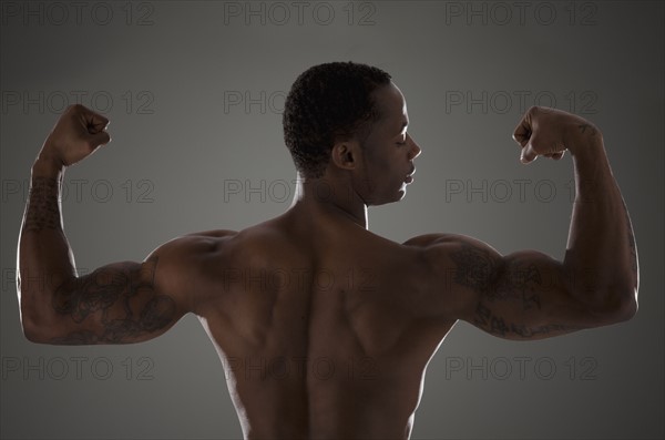 Physically fit man flexing his triceps. Photographe : Mike Kemp