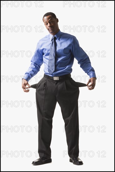 Businessman pulling out his empty pockets. Photographe : Mike Kemp