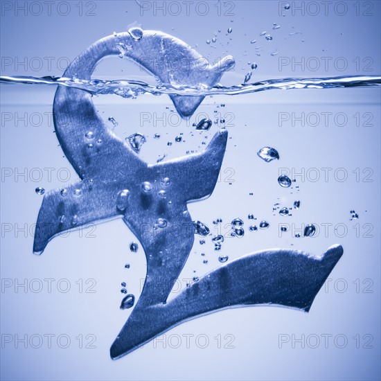 British pound symbol sinking in water. Photographe : Mike Kemp