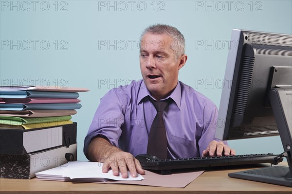 Overworked man sitting at his desk. Photographe : RTimages