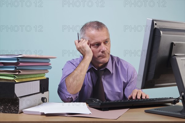 Overworked man sitting at his desk. Photographe : RTimages