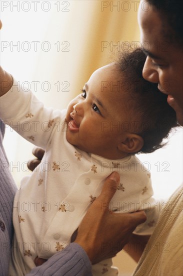 Close-up of mother and father holding their baby. Photographe : Rob Lewine