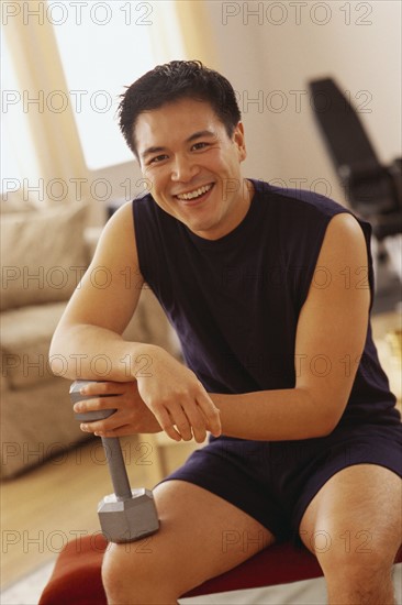 Portrait of a man holding a dumbbell. Photographe : Rob Lewine