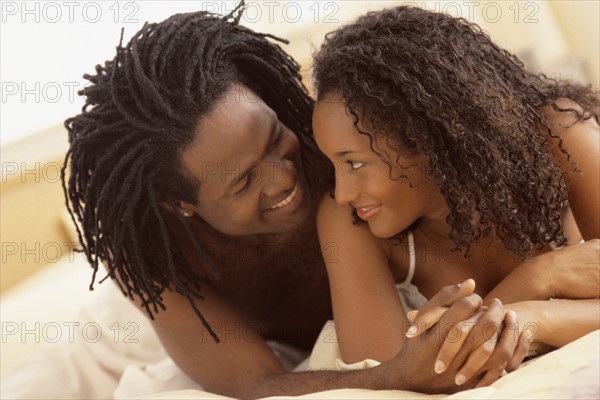 Couple embracing on their bed. Photographe : Rob Lewine