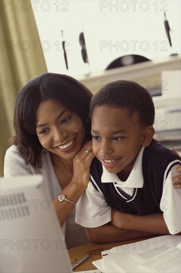 Mother and son looking at computer together. Photographe : Rob Lewine