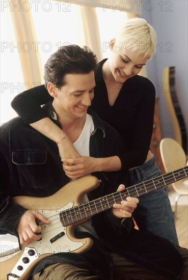 Woman listening to her boyfriend playing the electric bass. Photographe : Rob Lewine