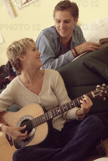 Man listening to girlfriend play guitar. Photographe : Rob Lewine