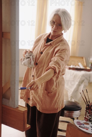 Elderly woman painting on a canvass. Photographe : Rob Lewine