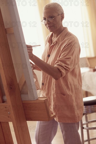 Elderly woman painting on a canvass. Photographe : Rob Lewine