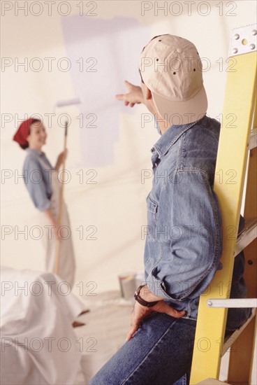 Couple painting the walls in their home. Photographe : Rob Lewine